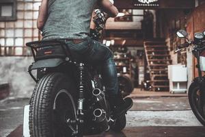 su il modo per box auto. avvicinamento posteriore Visualizza di uomo seduta su il suo bicicletta con motociclo box auto nel il sfondo foto