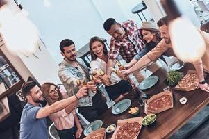 superiore Visualizza di giovane persone nel casuale indossare Esprimere a gesti e sorridente mentre avendo un' cena festa in casa foto