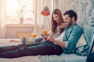 contento insieme. bellissimo giovane coppia avendo prima colazione mentre la spesa tempo nel letto a casa foto