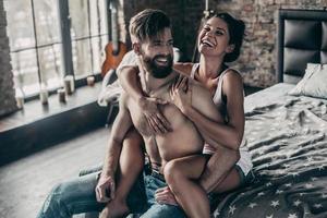 contento insieme. attraente giovane coppia sorridente e avendo divertimento insieme mentre bellissimo ragazza conservazione braccia in giro A petto nudo uomo foto