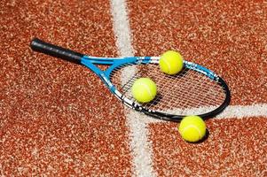 tempo per giocare a. avvicinamento di tennis racchetta e tre tennis palle posa su il Tribunale foto