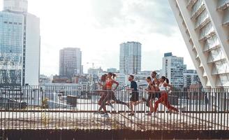 pieno lunghezza di giovane persone nel gli sport capi di abbigliamento jogging mentre esercizio su il ponte all'aperto foto