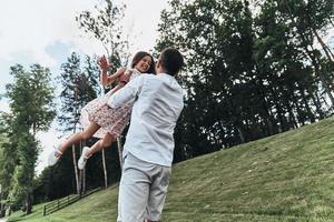 volante lontano. giovane amorevole padre trasporto il suo sorridente figlia mentre la spesa gratuito tempo all'aperto foto