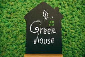 verde Casa. avvicinamento di Casa sagomato lavagna con mano scrittura testo a muschio sfondo foto