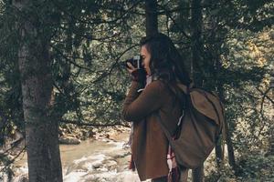 raccolta visualizzazioni. giovane moderno donna con zaino Fotografare natura mentre escursioni a piedi nel il boschi foto
