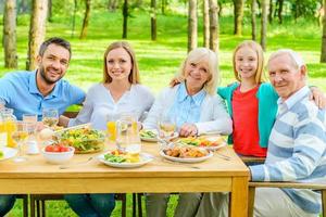 famiglia insieme. contento famiglia di cinque persone bonding per ogni altro e sorridente mentre seduta a il cenare tavolo all'aperto foto