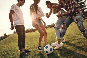gruppo di giovane sorridente persone nel casuale indossare combattente per il palla mentre giocando calcio all'aperto foto
