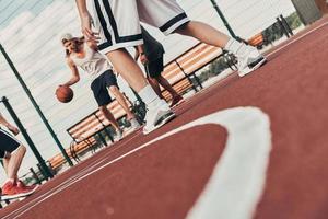 è venuto per giocare difficile. gruppo di giovane uomini nel gli sport capi di abbigliamento giocando pallacanestro mentre la spesa tempo all'aperto foto