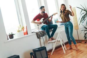 contento giovane coppia nel casuale capi di abbigliamento bonding insieme e sorridente mentre giocando il chitarra foto