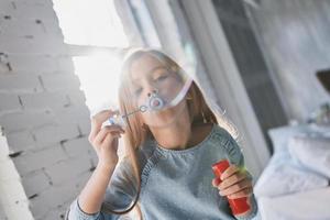 carino poco ragazza soffiaggio un' sapone bolla mentre la spesa tempo a casa foto