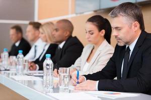 attività commerciale conferenza. lato Visualizza di attività commerciale persone scrittura qualcosa nel loro Nota pastiglie mentre seduta nel un' riga foto