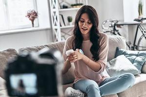 analisi nuovo bellezza Prodotto. bellissimo giovane donna analisi bellezza Prodotto e sorridente mentre fabbricazione sociale media video foto