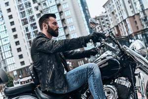 appena lui e il strada. bello giovane uomo seduta su il motocicletta mentre la spesa tempo all'aperto foto