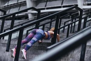 mattina allenamento. moderno giovane donna nel sport capi di abbigliamento conservazione tavola posizione mentre esercizio su il passaggi all'aperto foto