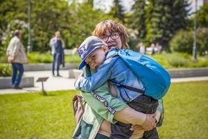 un' lunatico bambino coccole su per il suo giovane nonna nel il parco. il donna si sente spiacente per il ragazzo nel sua braccia. interazioni. selettivo messa a fuoco. foto