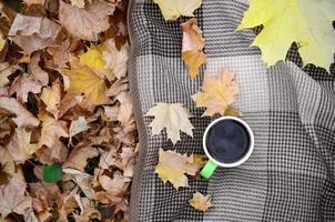 autunno le foglie e caldo cottura a vapore tazza di caffè bugie su scacchi plaid all'aperto foto