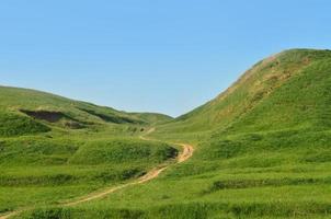 paesaggio con un' calpestata sentiero, passaggio attraverso un' meraviglioso verde montagnoso terreno. foto di bellissimo paesaggistico sollievo spazio con un' magro sentiero