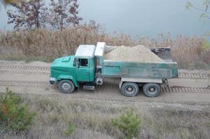 cumulo di rifiuti camion trasporti sabbia e altro minerali nel il estrazione cava. pesante industria foto