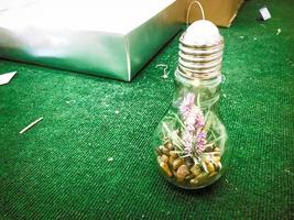 un' piccolo verde biologico pianta fiore cresce dentro un' bicchiere leggero lampadina. concetto ecologia, protezione di il pianeta foto