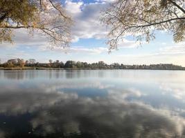 autunno paesaggio bellissimo con alberi e giallo le foglie su il lago contro il blu cielo su un' soleggiato giorno foto