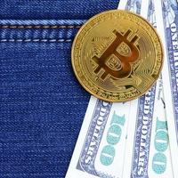 d'oro bitcoin e dollaro fatture bugie su un' blu jeans tessuto. nuovo virtuale i soldi. nuovo crypto moneta nel il modulo di il monete foto