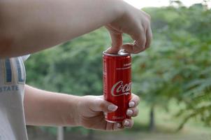 Kharkov. Ucraina - Maggio 2, 2019 caucasico donna detiene rosso Coca Cola lattina può con verde giardino sfondo foto