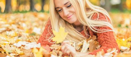 donna bugie giù su le foglie a il autunno parco foto