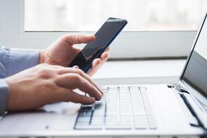 uomo dietro a il computer portatile con smartphone foto