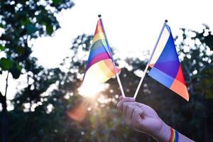 arcobaleno bandiera e braccialetti Tenere nel mani, morbido e selettivo messa a fuoco, concetto per LGBTQ generi celebrazioni e chiamata tutti persone per rispetto umano diritti nel orgoglio mese in giro il mondo. foto