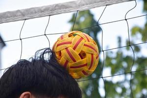 giovane sud-est asiatico maschio sepak takraw giocatore utilizzando il suo giusto mano per hold palla su il suo testa, all'aperto sepak takraw giocando dopo scuola, morbido e selettivo messa a fuoco su sfera. foto