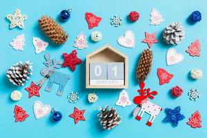 superiore Visualizza di di legno calendario circondato con nuovo anno giocattoli e decorazioni su blu sfondo. il primo di gennaio. Natale tempo concetto foto