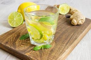 soda allo zenzero biologico in un bicchiere con limone e lime foto