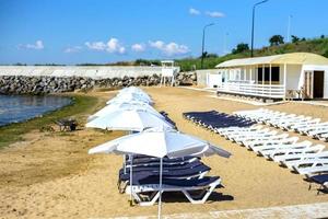 bellissimo vuoto spiaggia con righe di sole letti sotto cannuccia ombrelli foto