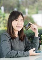 giovane donna seduta mostrando carta di credito foto