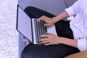 felice casual bella donna che lavora su un computer portatile seduto sul letto in casa. foto