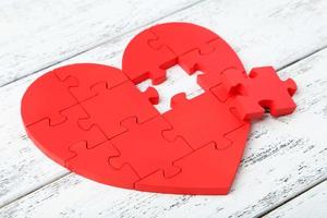 cuore puzzle rosso su fondo di legno bianco