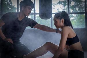 donna esercizio con allenatore a boxe e se stesso difesa lezione, studio, Fumo su sfondo. femmina e maschio combattimento foto