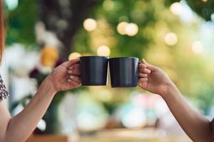 avvicinamento Immagine di un' persone tintinnante caffè tazze insieme nel bar foto