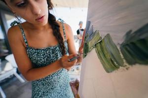 giovane donna artista vernici con un' spatola su il tela foto
