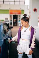 donna Riempimento sua auto con carburante a un' gas stazione foto