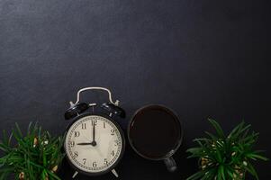 tazza di caffè e un orologio sulla scrivania foto