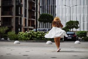 bellissimo bella donna nel bianca vestito a piedi a città strada foto