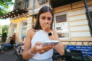 bella donna un urbano strada per leggere un sms su sua mobile Telefono foto