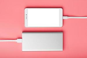 energia banca addebiti il tuo smartphone su un' rosa sfondo. universale esterno batteria per gadget gratuito spazio e minimalista composizione. foto