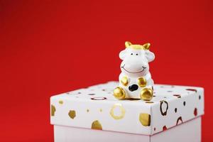 mucca figurina su un' regalo scatola su un' rosso sfondo, con gratuito spazio. foto