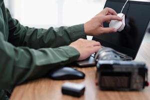 vicino su mano fotografo uso colore calibrazione macchina su tenere sotto controllo il computer portatile computer per Schermo calibrazione e telecamera ,batteria su il legna tavolo foto