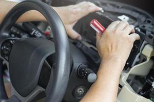 vicino su mano tecnico rimuovere auto tachimetro con vite autista nel lato cabina dai un'occhiata e sostituire nuovo parti per sostituire il rotto nel auto servizio negozio foto