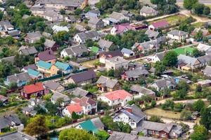 vista panoramica aerea del villaggio verde con case, fienili e strada sterrata nella foresta foto