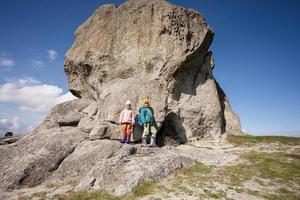 esplorando natura. fratello e sorella indossare zaino escursioni a piedi vicino grande pietra nel collina. pidkamin, Ucraina. foto