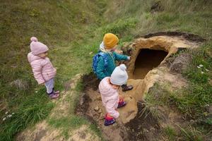 tre bambini Esplorare calcare pietra grotta a montagna. foto